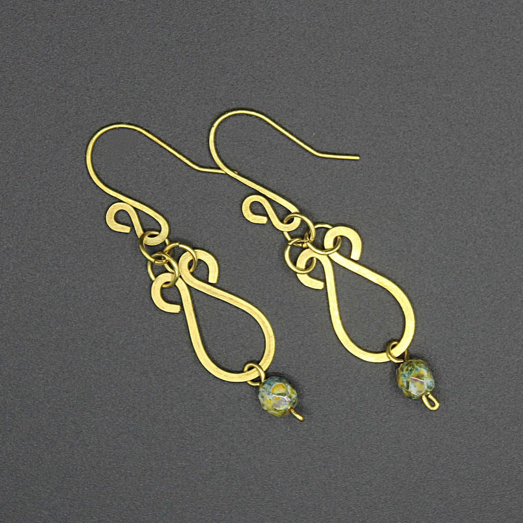 Hammered brass teardrop earrings with mottled yellow/blue bead drops on a gray background.