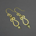 Hammered brass teardrop earrings with mottled yellow/blue bead drops on a gray background.