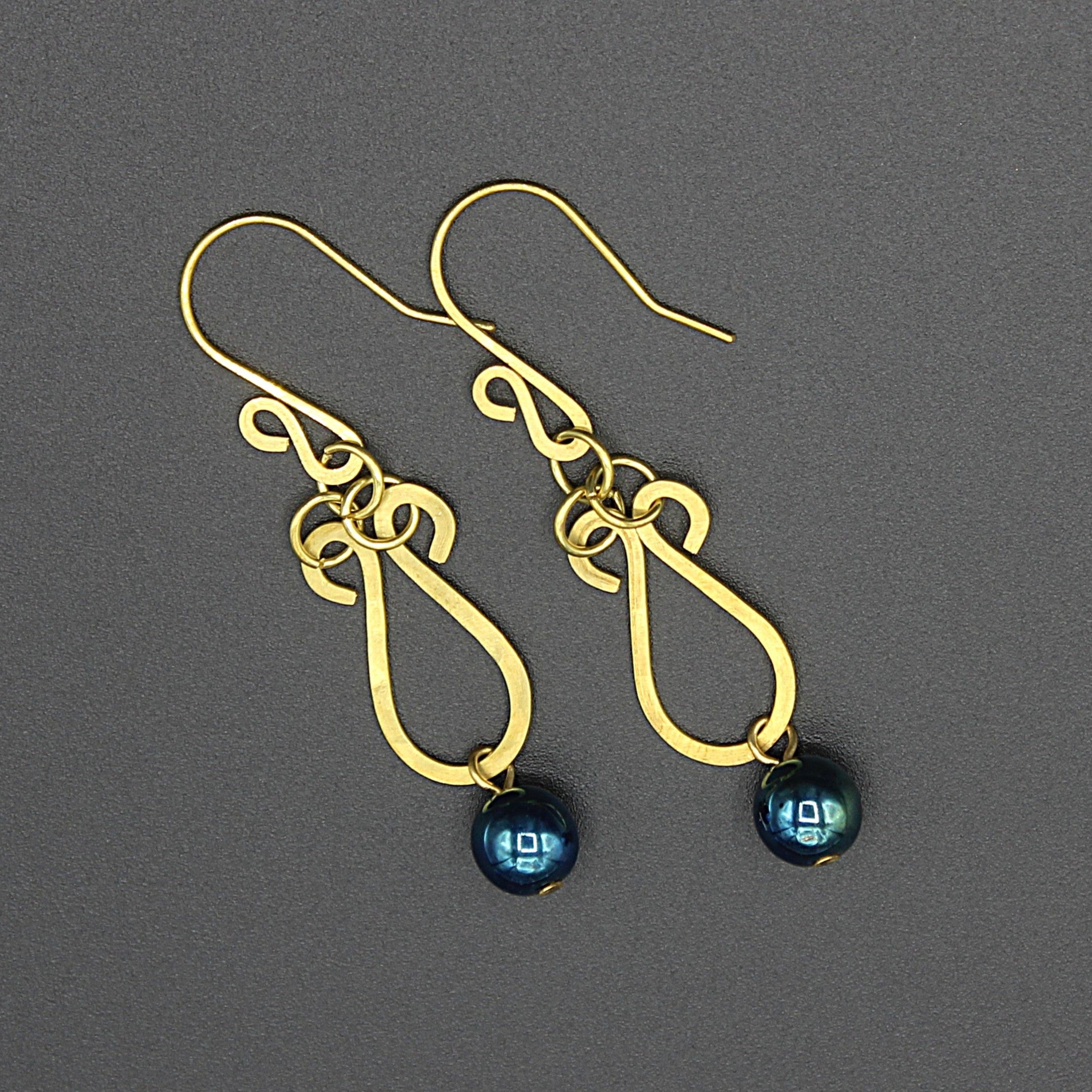 Hammered brass teardrop earrings with metallic dark teal bead drops on a gray background.