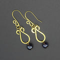 Hammered brass teardrop earrings with dark purple bead drops on a gray background.