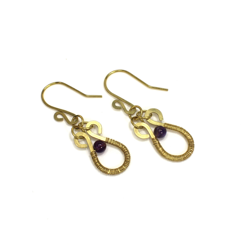 Hammered brass wire earrings with purple amethyst gemstones and wire wrapping on a white background
