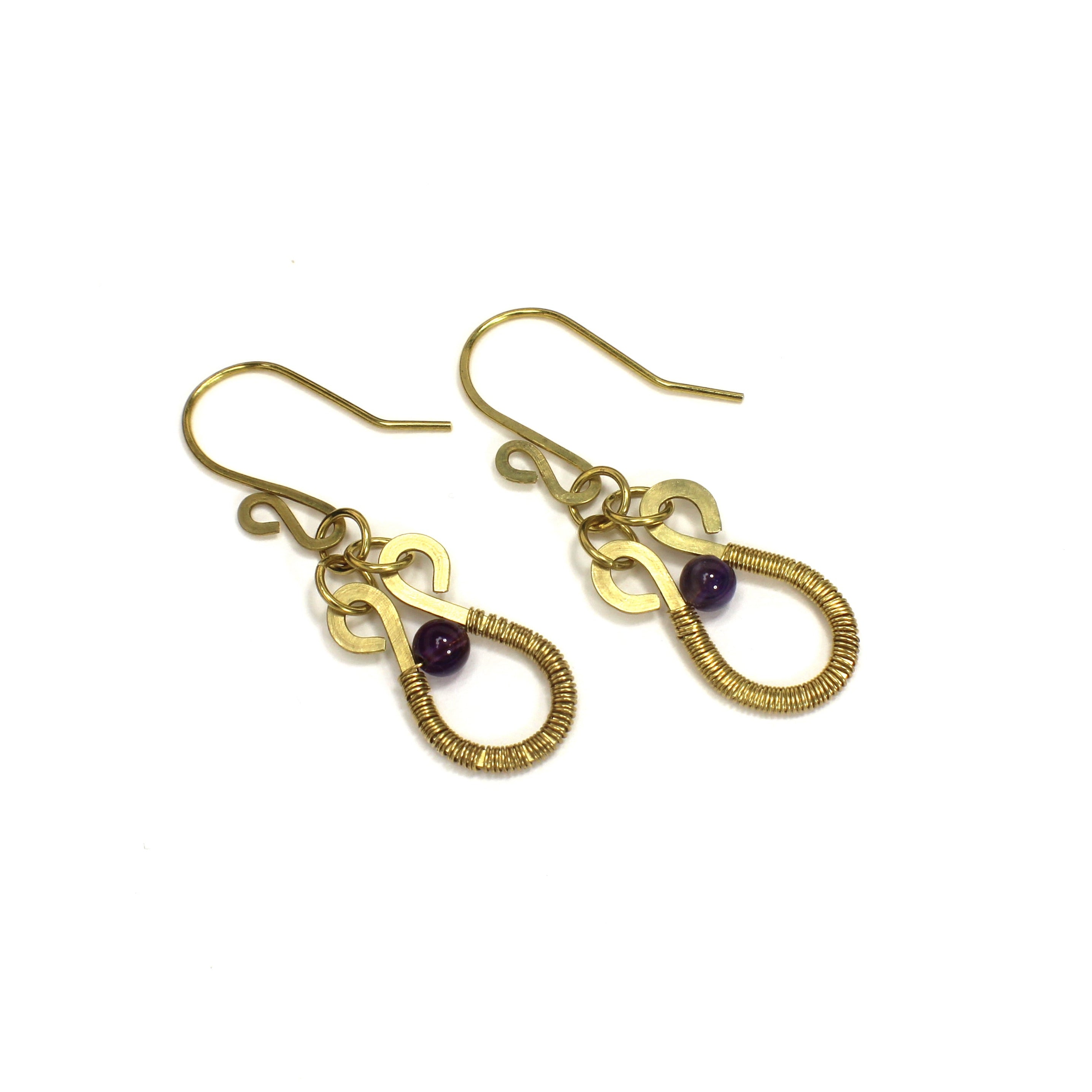 Hammered brass wire earrings with purple amethyst gemstones and wire wrapping on a white background