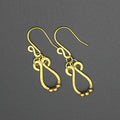 Hammered brass teardrop earrings with small brass bead accents on a gray background.