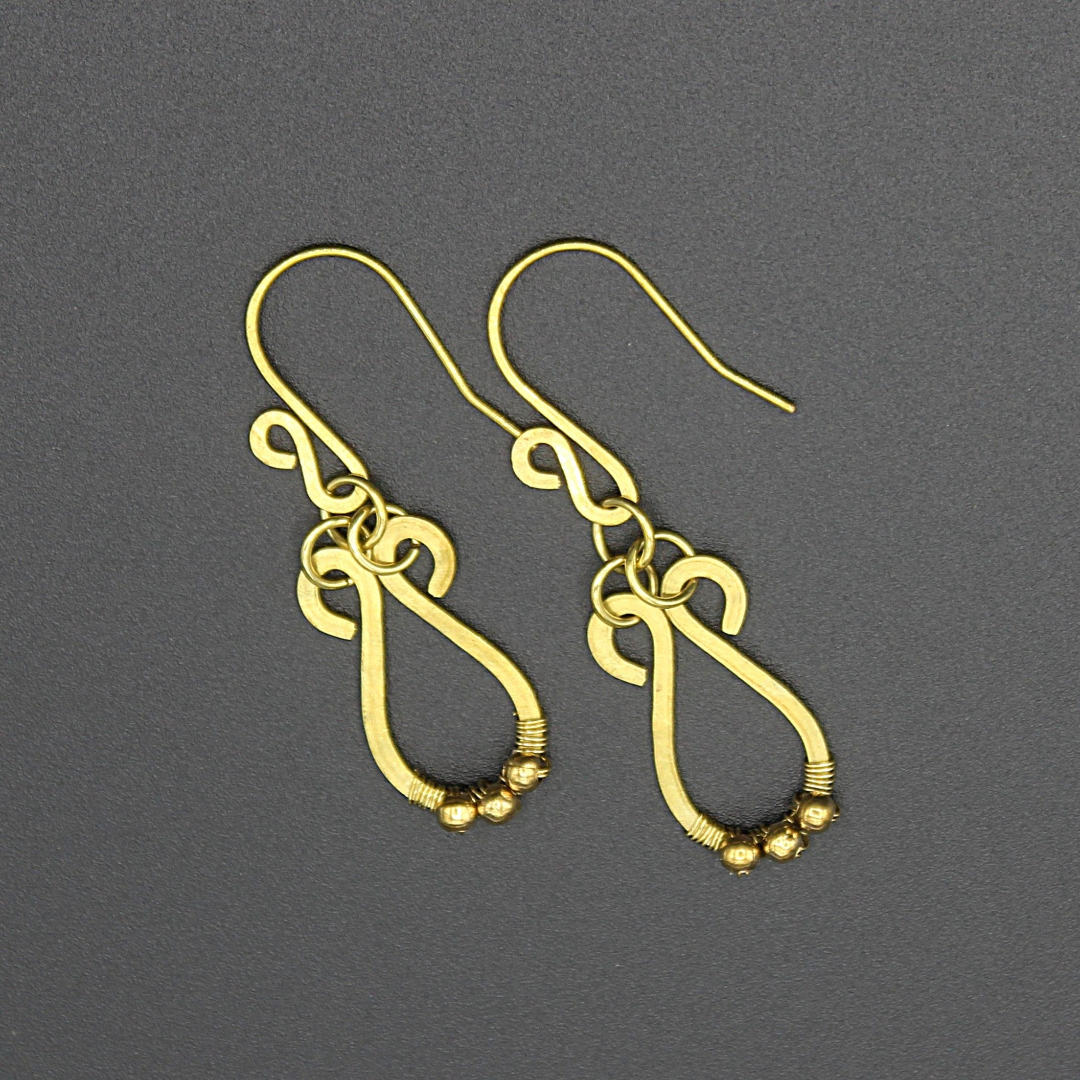 Hammered brass teardrop earrings with small brass bead accents on a gray background.