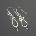 Hammered silver teardrop earrings with faceted blue bead drops on a gray background.