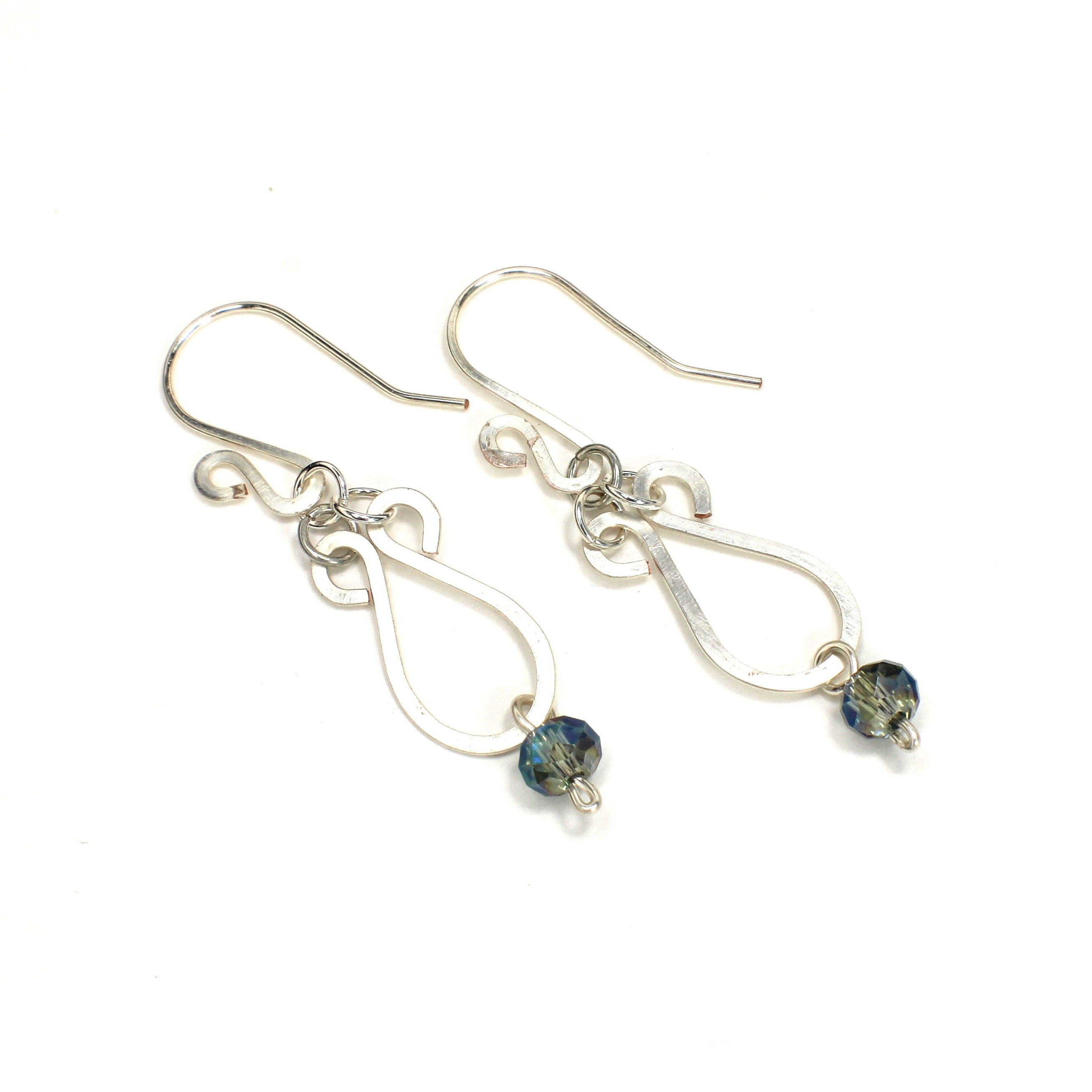 Hammered silver teardrop earrings with faceted blue bead drops on a white background