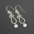 Hammered silver earrings with pale blue bead drops on a gray background.