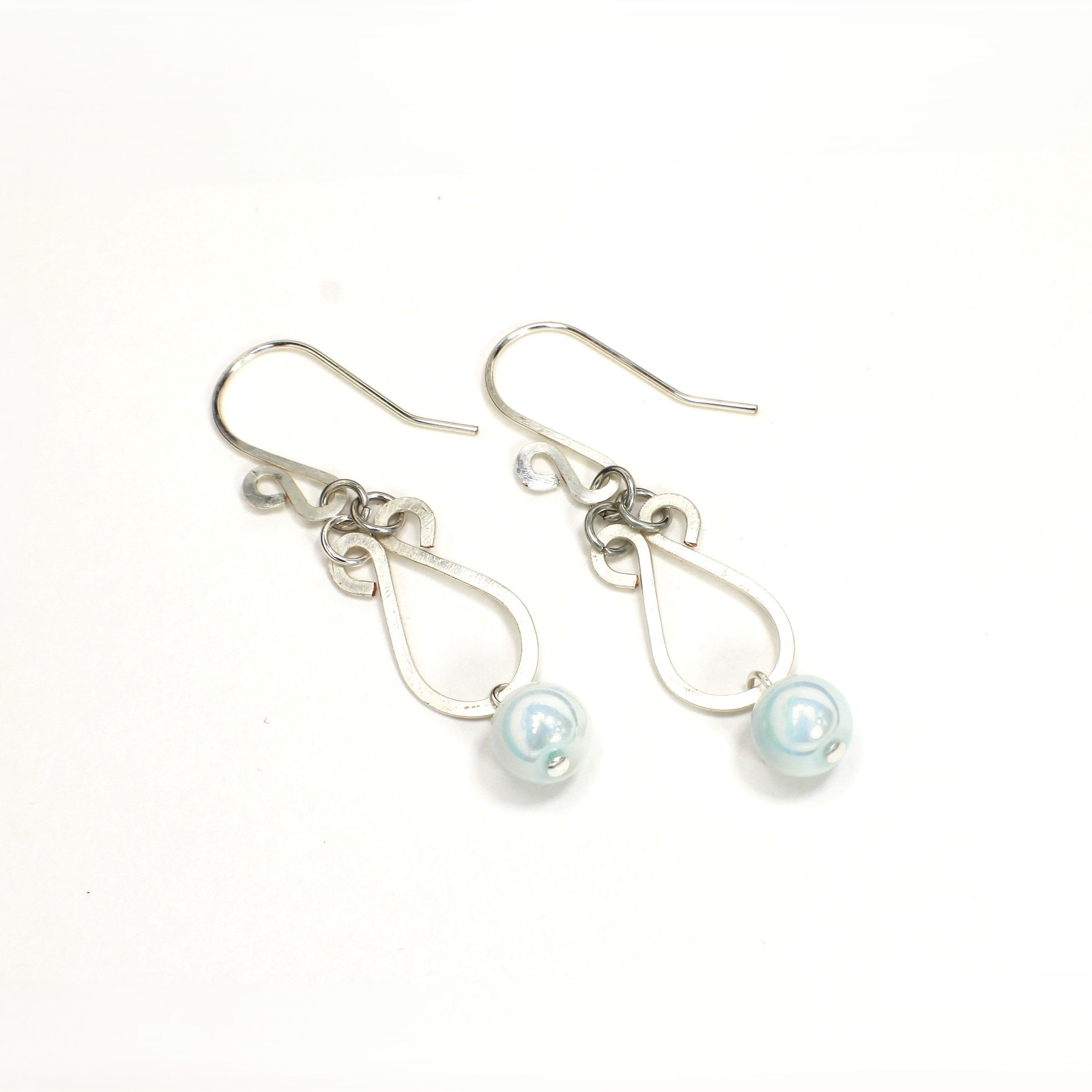 Hammered silver earrings with pale blue bead drops on a white background