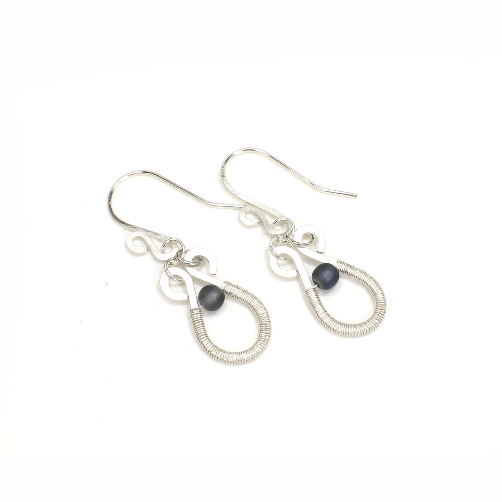 Hammered silver teardrop earrings with wire-wrapped blue bead accents on a white background