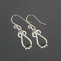 Hammered silver teardrop earrings with small silver bead accents on a gray background.