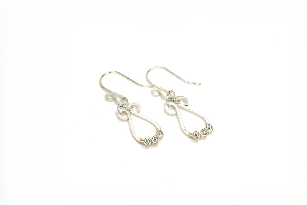 Hammered silver teardrop earrings with small silver bead accents on a white background