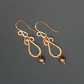 Hammered copper teardrop earrings with metallic finish faceted glass beads on a gray background.