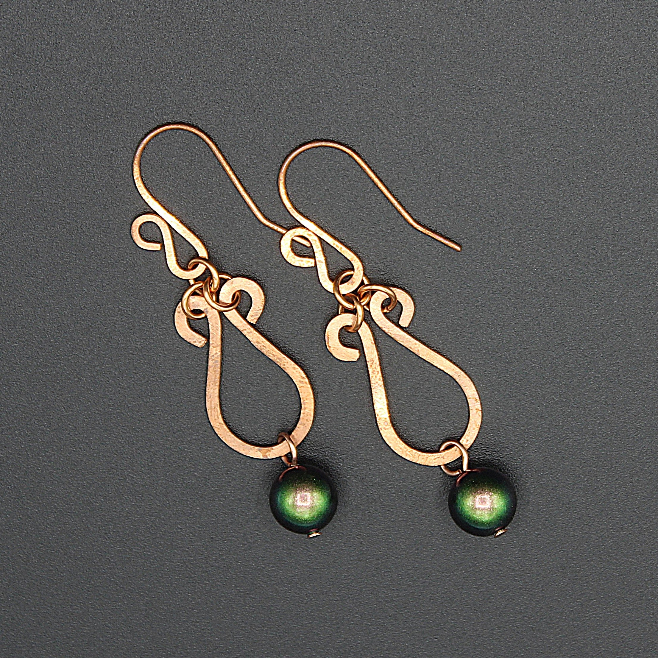 Hammered copper teardrop earrings ending in green glass pearl drops.
