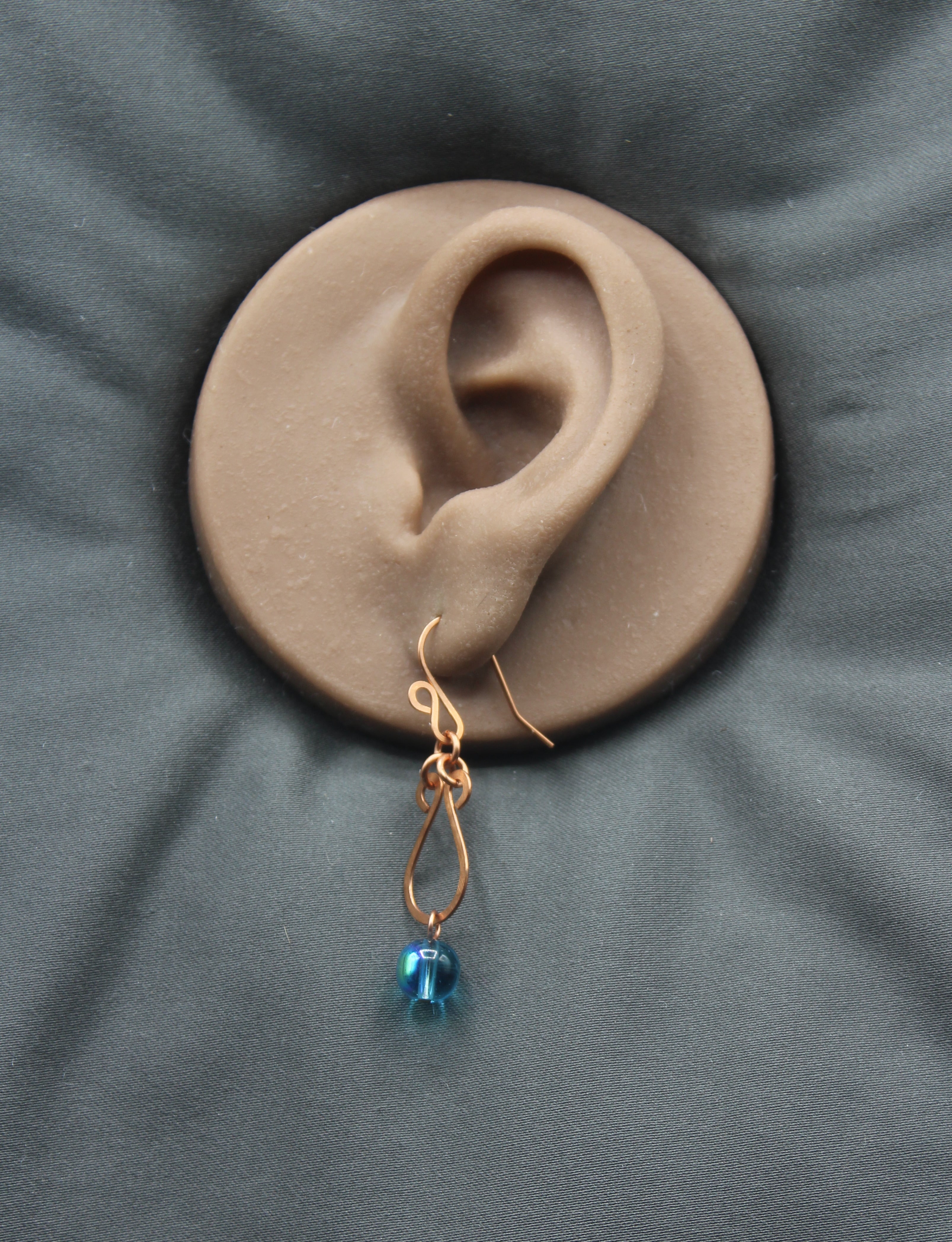 Hammered copper teardrop earring with a blue transparent bead drop
