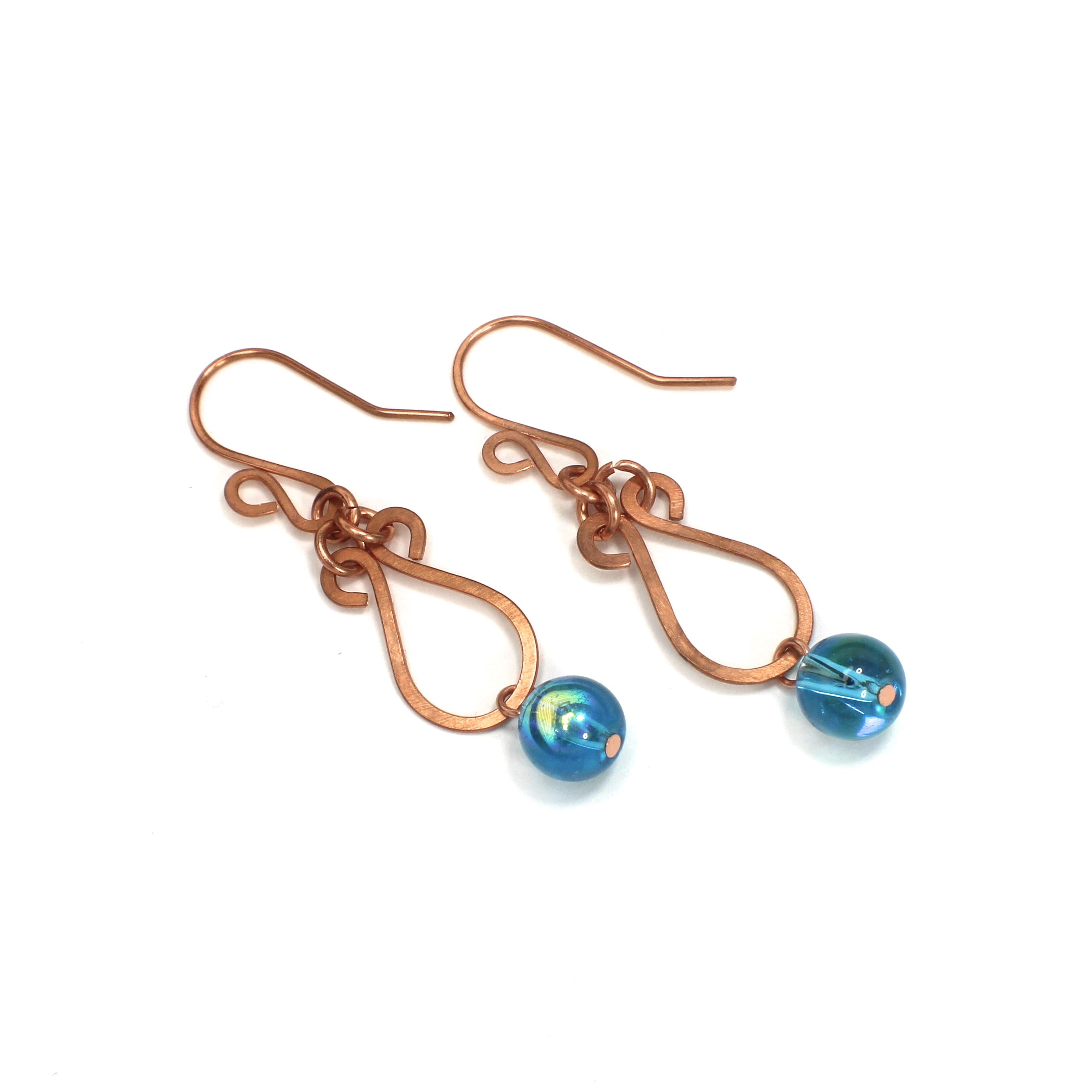 Hammered copper teardrop earrings with blue transparent bead drops on a white background