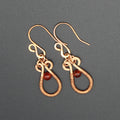 Flat wire copper teardrop earrings wire wrapped with carnelian bead accents on a gray background.
