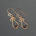 Hammered copper teardrop earrings with tiny wrapped beads on a gray background