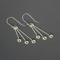 Silver wire earrings with hanging triple spirals on a gray background