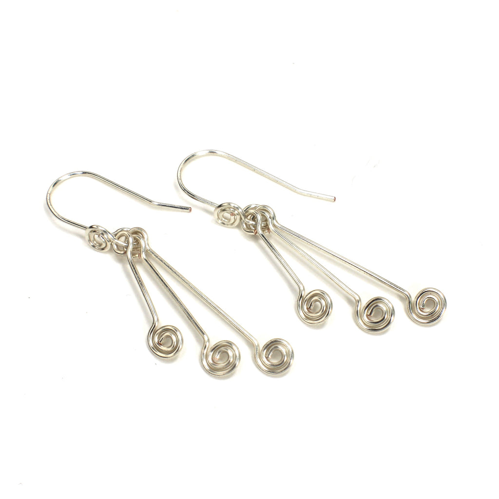 Pair of silver wire earrings with triple spirals on a white background