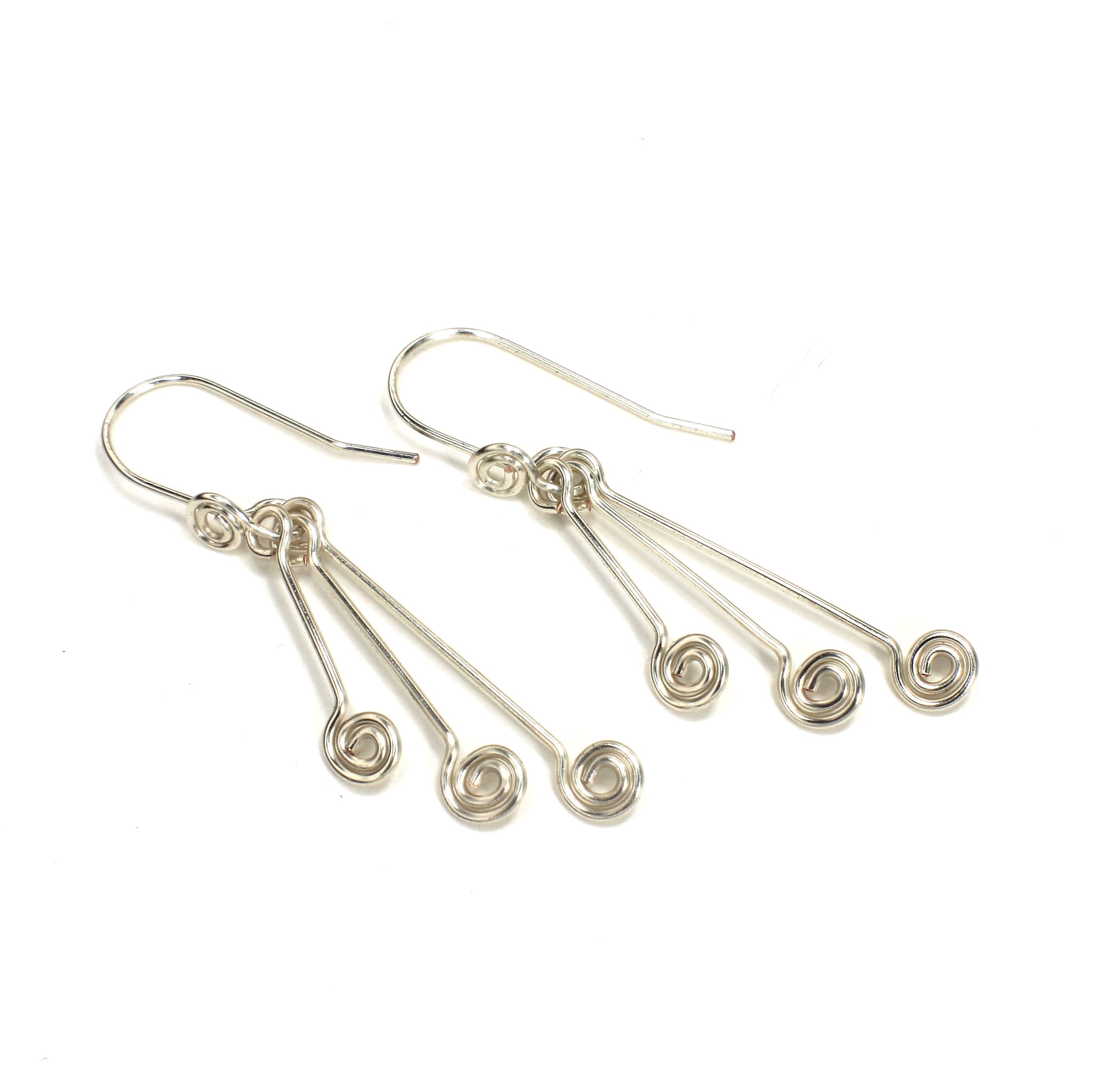 Pair of silver wire earrings with triple spirals on a white background