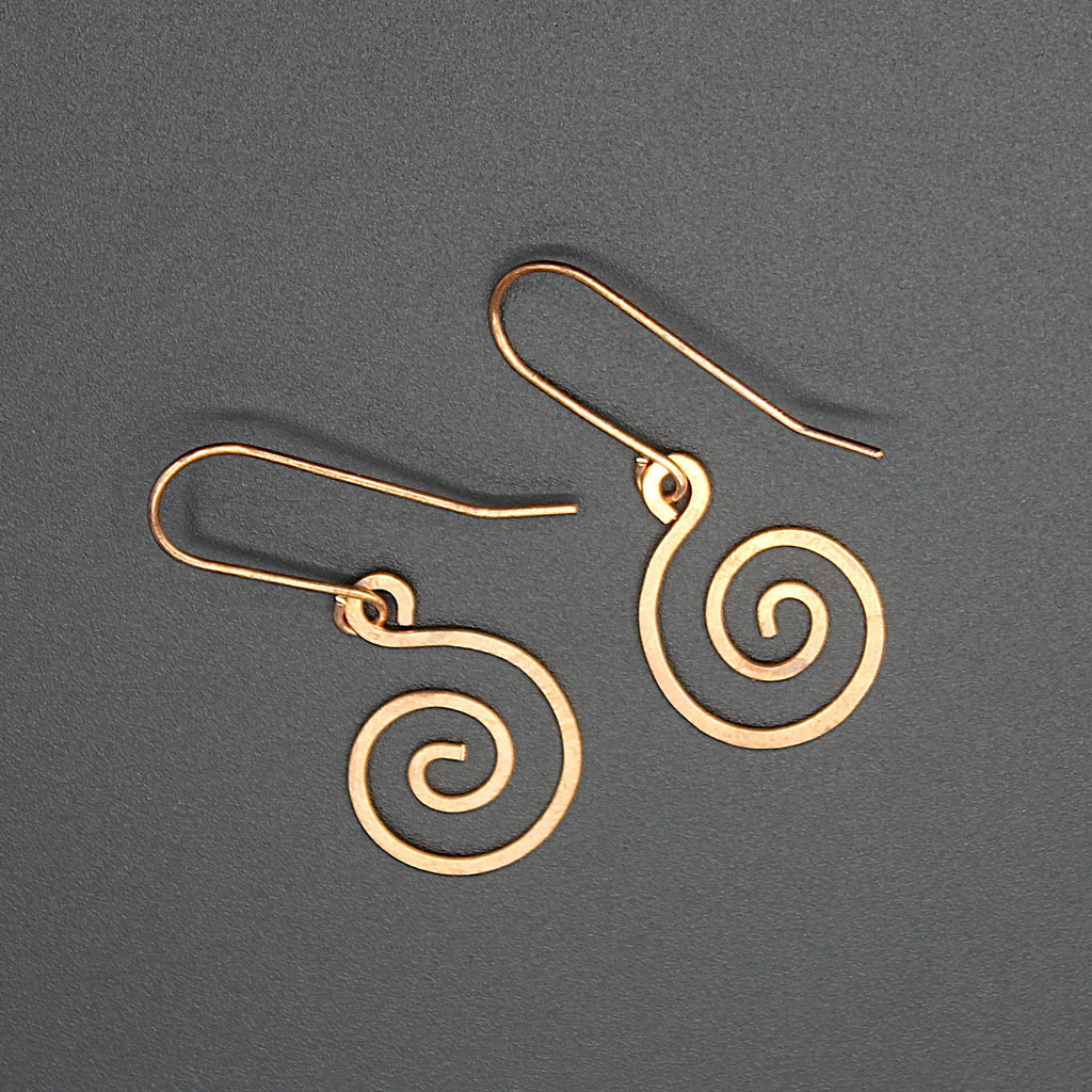 Copper spiral earrings on a gray background