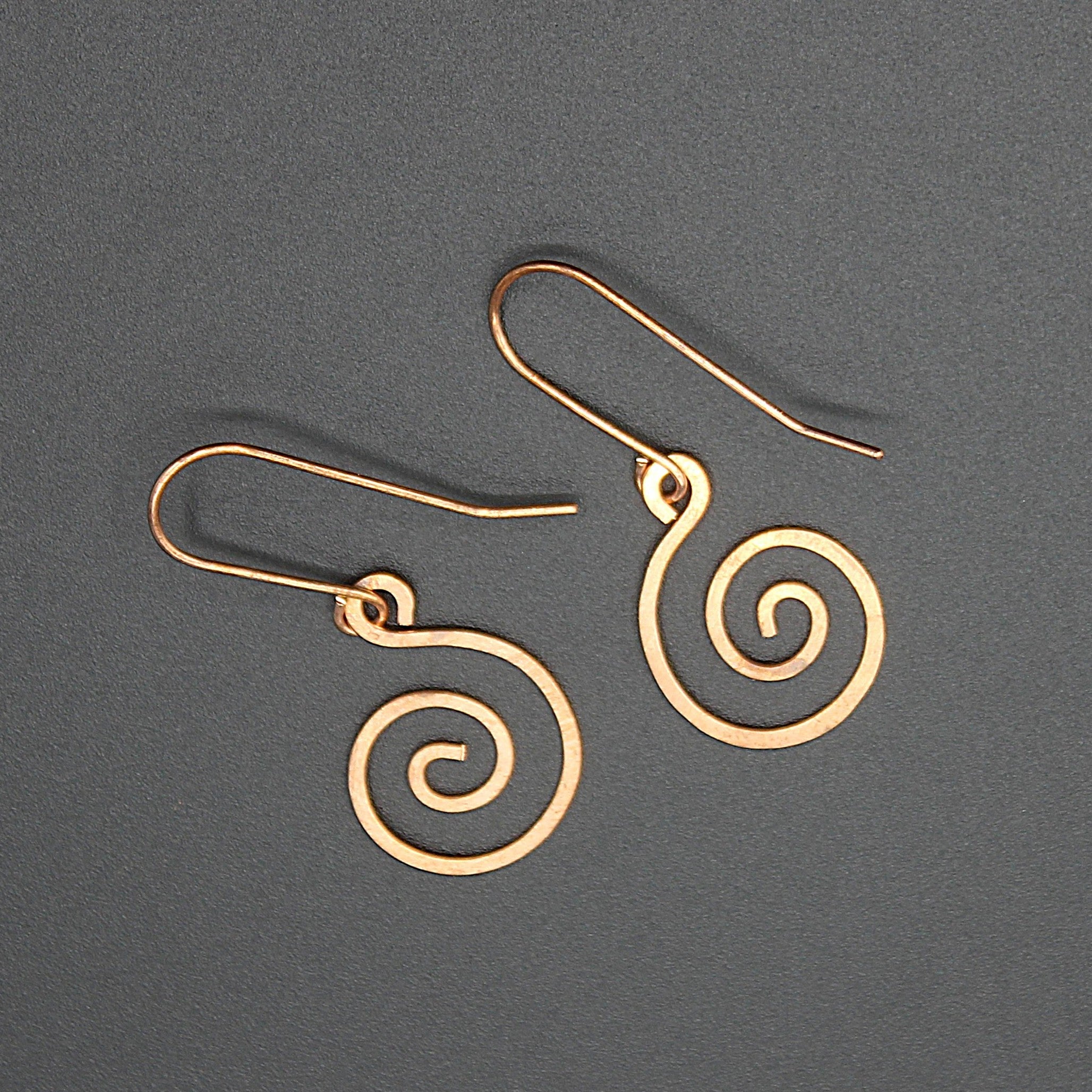 Copper spiral earrings on a gray background