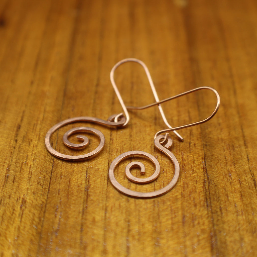 Copper spiral earrings on a wooden surface