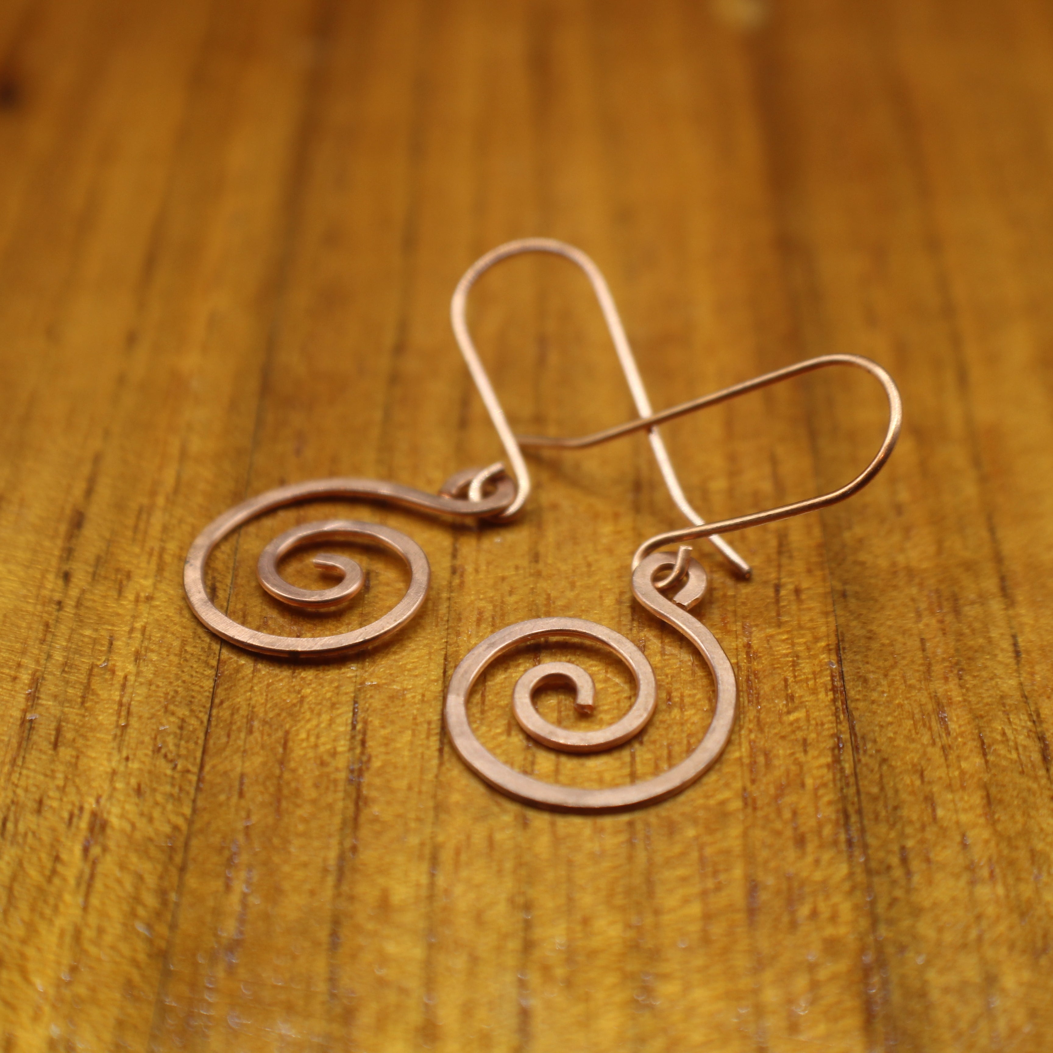 Copper spiral earrings on a wooden surface