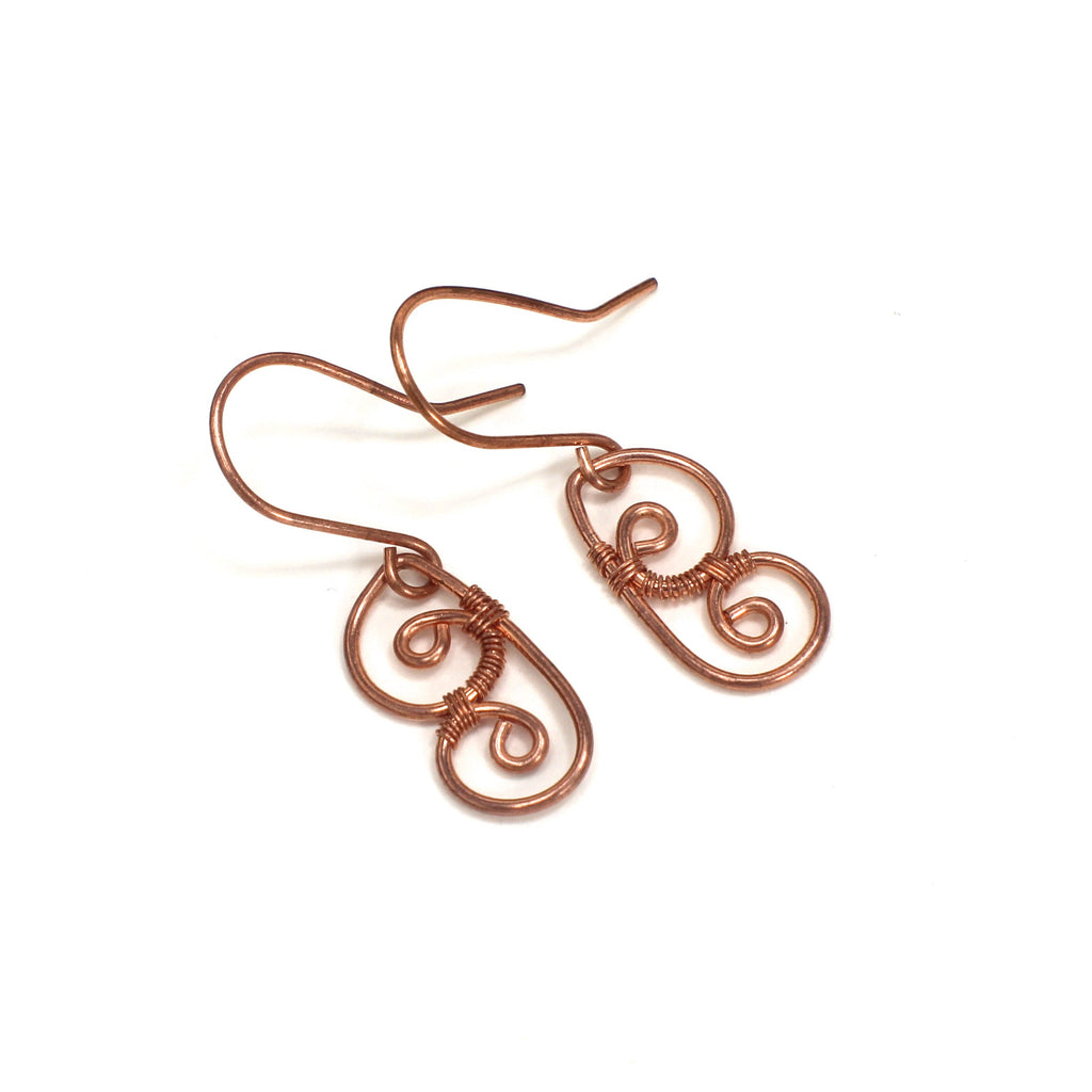 Pair of copper wire earrings shaped as abstract butterfly wings on a white background