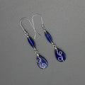 Pair of sapphire blue teardrop earrings with stainless steel wire details on a gray background