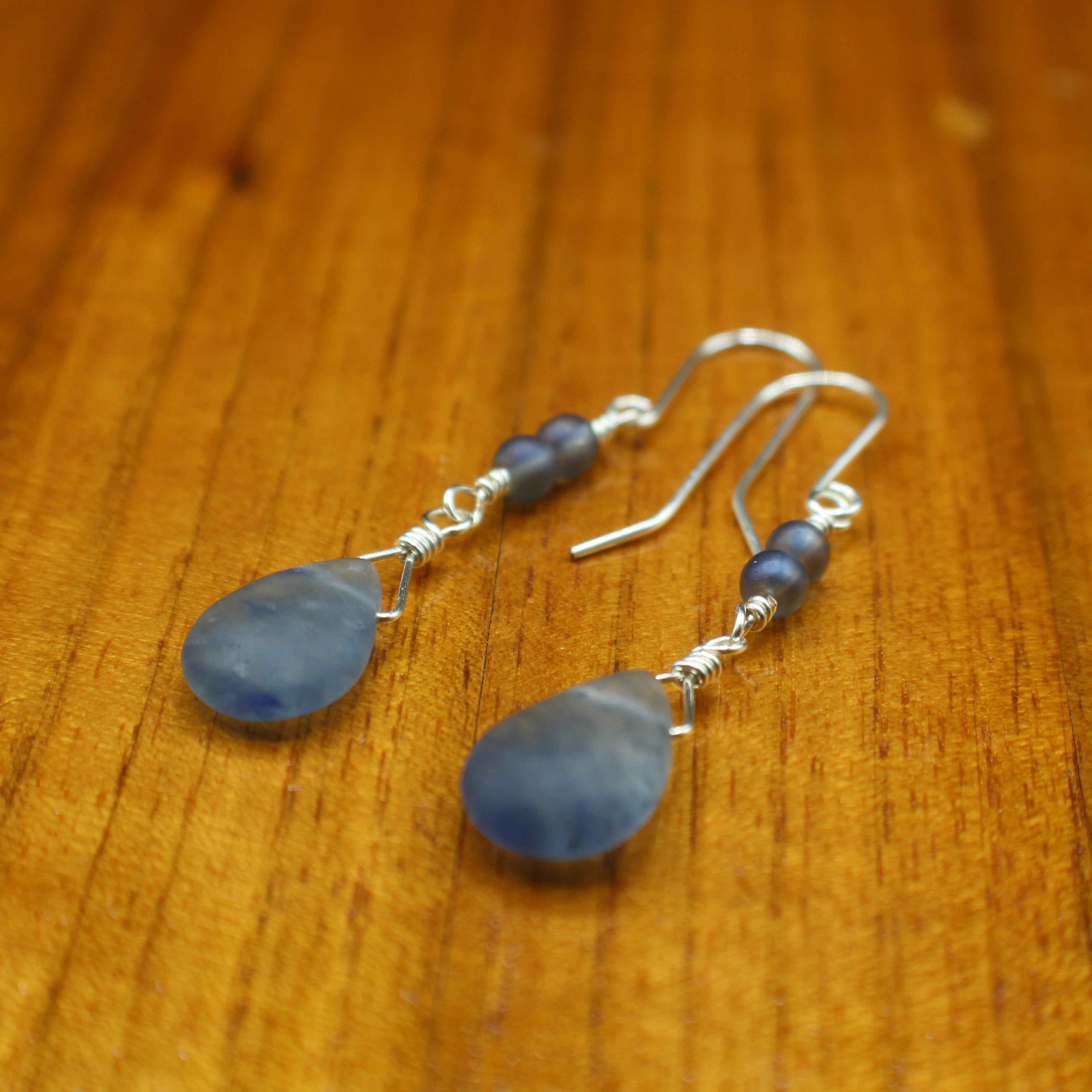 Blue teardrop earrings on a wooden surface
